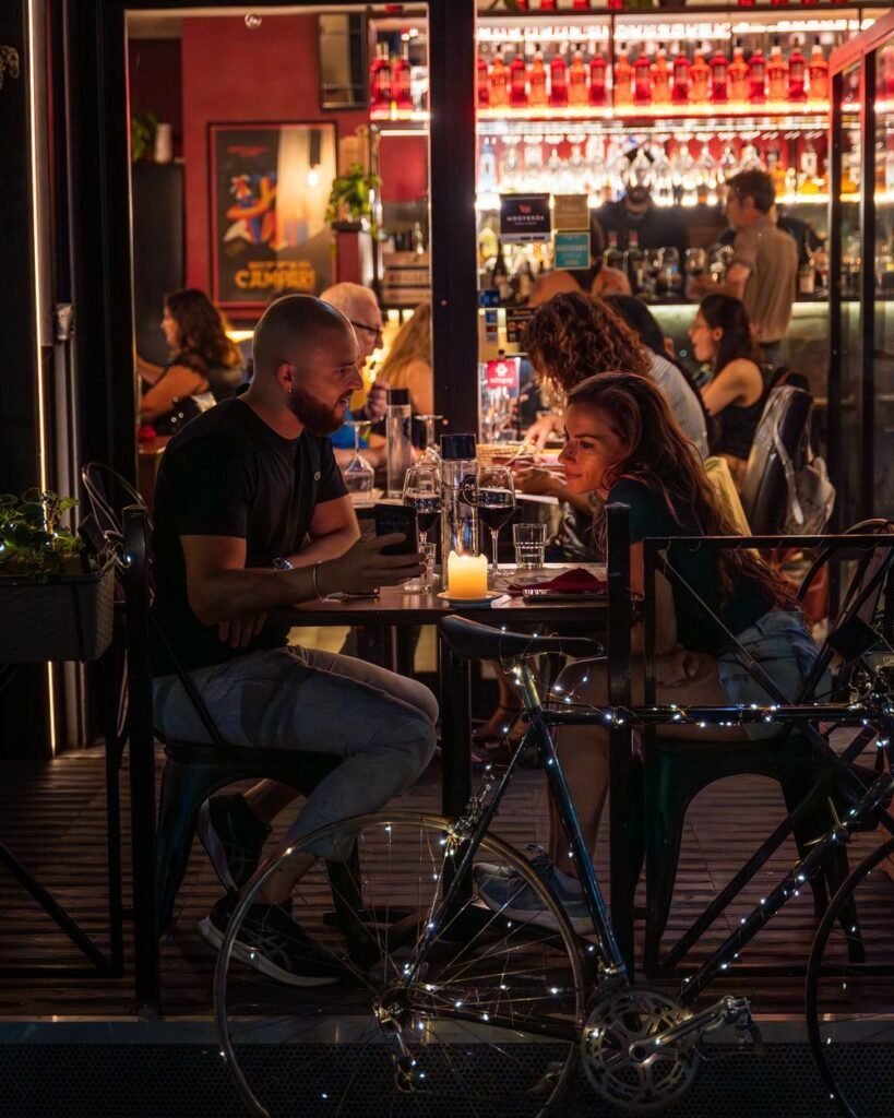 Los comensales en las mesas al aire libre del bistró en un ambiente nocturno